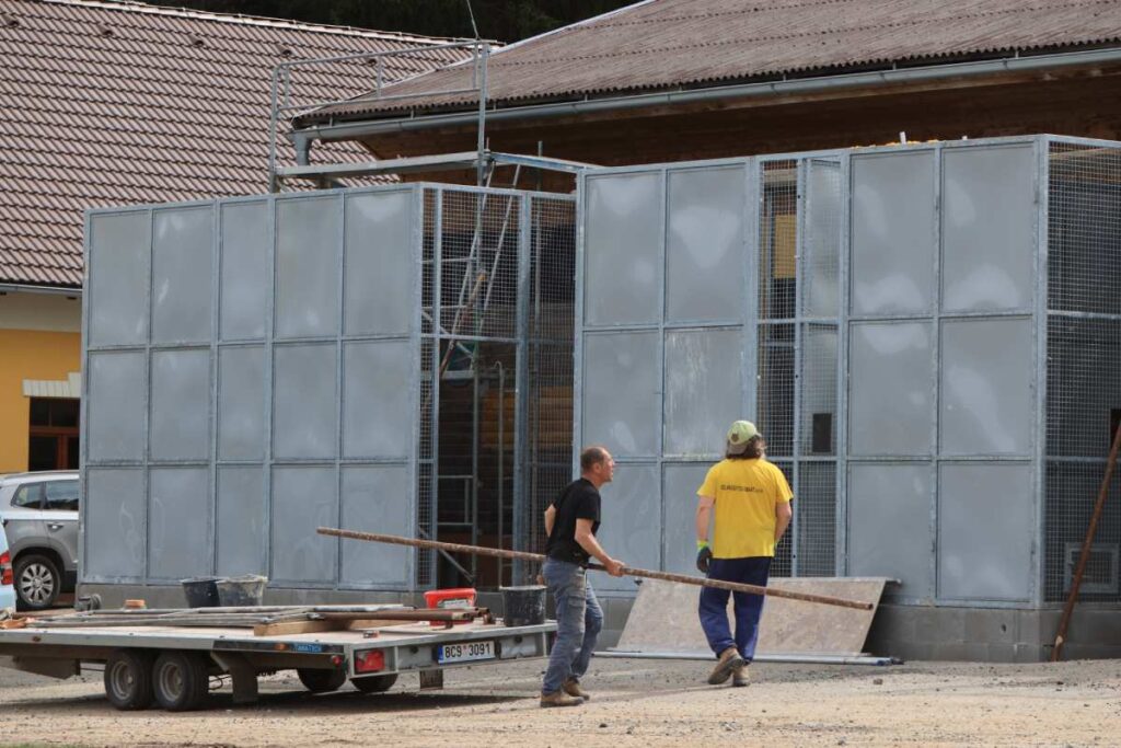 Stavební práce v záchranné stanici Klášterec, dělníci manipulují s materiálem při rekonstrukci.